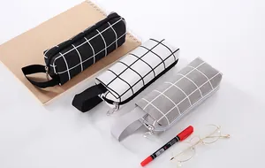 Detail view of three minimalist grid canvas pencil cases in black, white, and gray
