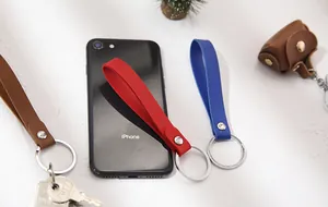 Handmade leather loop keychains in red, blue, and brown shown with a smartphone