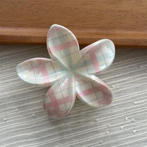 Macro view of a sweet flower-shaped hair claw clip with pink and blue plaid patterns