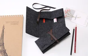 Dettaglio dell'astuccio a rotolo in feltro grigio con cinturino in pelle marrone e logo Yuelu