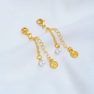 Detailopname van 24K vergulde verlengketting met een parel en een geluksmunt bedeltje