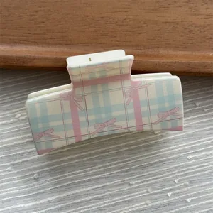 Detail view of a pastel plaid square hair claw clip with cute pink bow pattern