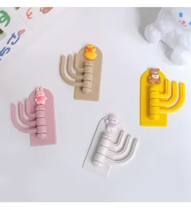 Macro view of four colorful cartoon swivel hooks with cute animal characters on wall.