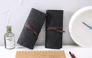 Dettaglio macro dell'astuccio in feltro grigio scuro con elegante chiusura a laccio marrone