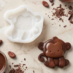 Detalle del molde de silicona de mono con una figura de chocolate sobre fondo de mármol.