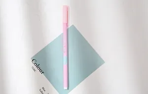 Detailed view of a pink minimalist gel pen with cute barrel text on aesthetic desk background