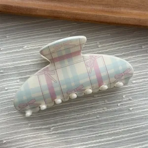 Close-up of a sweet plaid hair claw clip with pink bow pattern in macaron colors