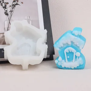 Vista detallada de un molde de silicona para casita de Navidad con vela azul y nieve
