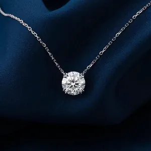 Close-up of a brilliant round moissanite pendant necklace on a deep blue silk background