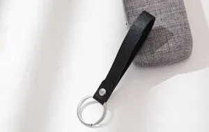 Detail view of a minimalist black leather strap keychain with a silver split ring