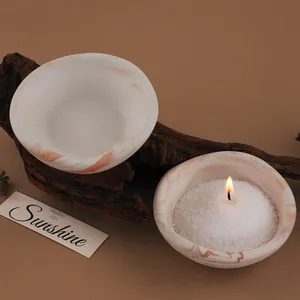 Close-up of marbled DIY storage bowls on a natural wood background with a candle