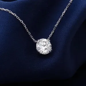 Macro view of a brilliant round-cut moissanite pendant on a delicate silver-toned chain.