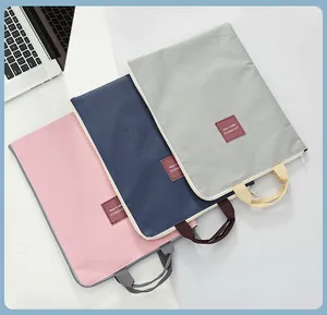 Set of three colorful canvas laptop bags in pink navy and grey on white desk