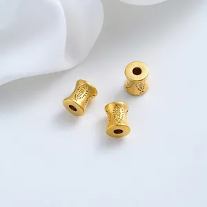 Dettaglio macro di perle a vita placcate in oro con motivo a pesci inciso per gioielli DIY