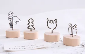 Close-up of creative wire memo holders with wooden bases in various artistic shapes.