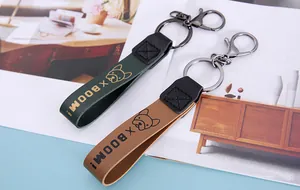 Close-up detail of leather car keychains with French Bulldog icon and X BOOM! print.