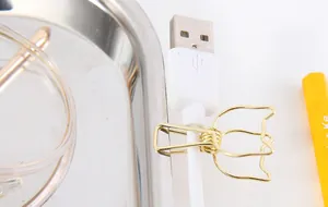 Nahaufnahme einer goldenen Metallklammer in Katzenform zur USB-Kabelorganisation