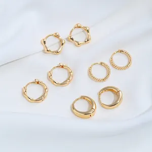 Primer plano de varios pendientes de aro de acero inoxidable dorado sobre tela