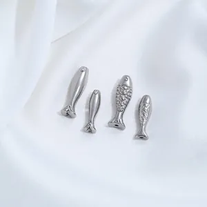Makro-Detail von silbernen Edelstahl-Fischanhängern mit glatten und geschuppten Texturen für DIY