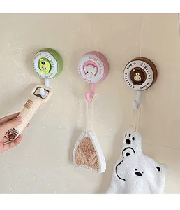 Close-up of cute cartoon animal wall hooks holding a bottle opener and towels on tiles