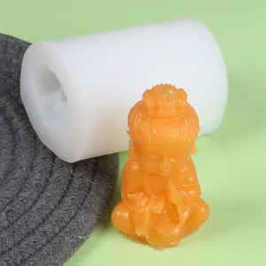 Detailed view of DIY silicone mold with finished orange monk wax figurine on green background.