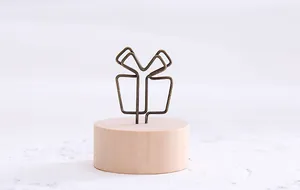 Detail view of a vintage gift-shaped iron wire memo clip with a minimalist wooden base