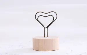 Close-up of a vintage heart-shaped metal wire clip on a circular wooden base holder.