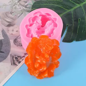 Detailed close-up of pink silicone baby mold with finished orange resin figurine