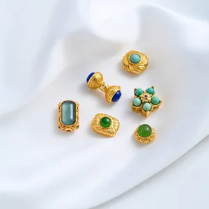 Detailopname van diverse 24K vergulde kralen met turquoise en groene stenen op witte doek