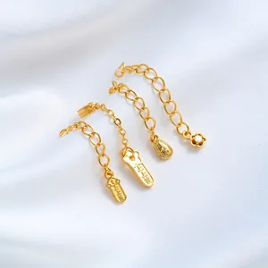 Detailed view of 24K gold plated jewelry extension chains with flower and tag charms