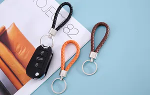 Braided leather keychain hand straps in black, orange and brown displayed on a magazine.