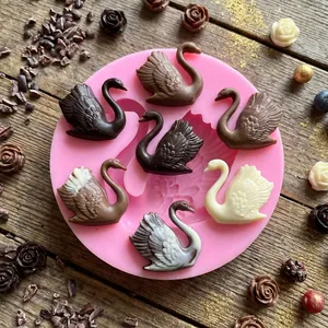 Detail view of swan-shaped silicone mold with textured chocolate swans on a wooden table
