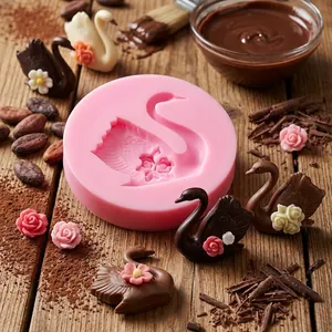 Detailed close-up of a pink swan with rose silicone mold and chocolate swans on wood