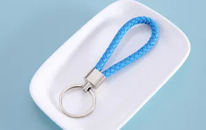 Close-up of a stylish sky blue braided leather keychain strap on a decorative white plate.