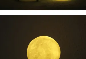 Macro shot of a 3D moon lamp glowing with warm yellow light and realistic craters.