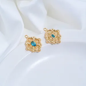 Detailed close-up of 14K gold-plated rhombus pendants with blue zircon and filigree detail
