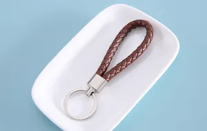 Close-up of brown braided leather keychain strap displayed on a white dish
