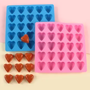 Detail of heart-shaped silicone molds in blue and pink with finished chocolates.