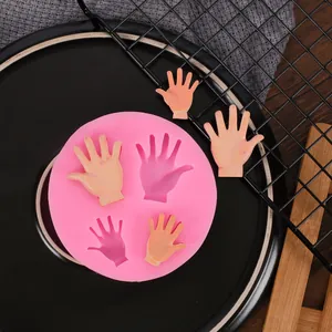 Detailansicht einer rosa Silikonform mit Handformen und fertigen Tonproben auf einem Teller.