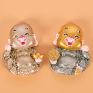Detailed view of two handcrafted laughing monk figurines in gold and silver finish