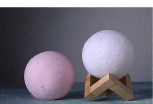 Close-up of pink and white 3D moon lamps with textured surface and wooden stand