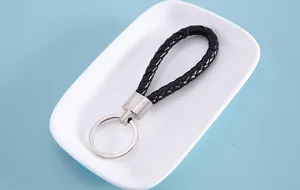 Close-up of a stylish black braided leather keychain with silver metal ring on a tray