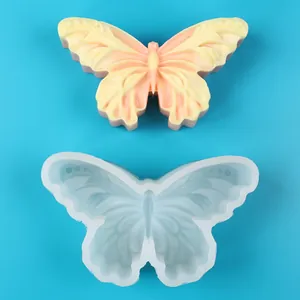 Detalle de un molde de silicona de mariposa con jabón artesanal sobre un fondo azul claro