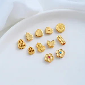 Close-up of 24K gold-plated copper charms in butterfly heart and gourd shapes for DIY