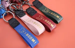 Détail de lanières de porte-clés en cuir coloré avec texte XBOOM! doré et icône de chien