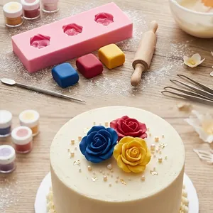Détail d'un moule en silicone rose et de roses en fondant sur un gâteau blanc.