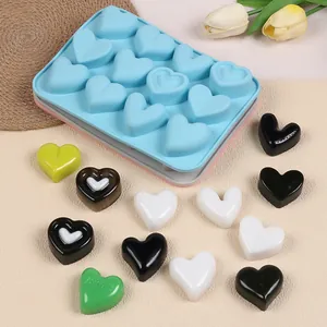 Detail view of heart-shaped silicone mold with colorful chocolate samples on a beige mat