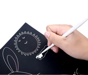 Primo piano di una mano che usa uno stilo su carta da grattare per rivelare i colori