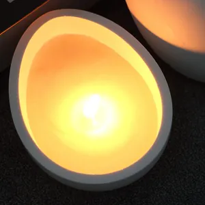 Dettaglio macro di una candela accesa in un supporto a forma di uovo fatto con uno stampo DIY