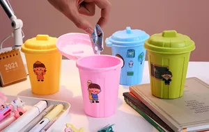 Usage detail of colorful lidded mini desktop trash can pen holder on a study desk.